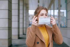 žena sa girpom stavlja masku- ehinacea za grip, prehladu i jak imuni sistem